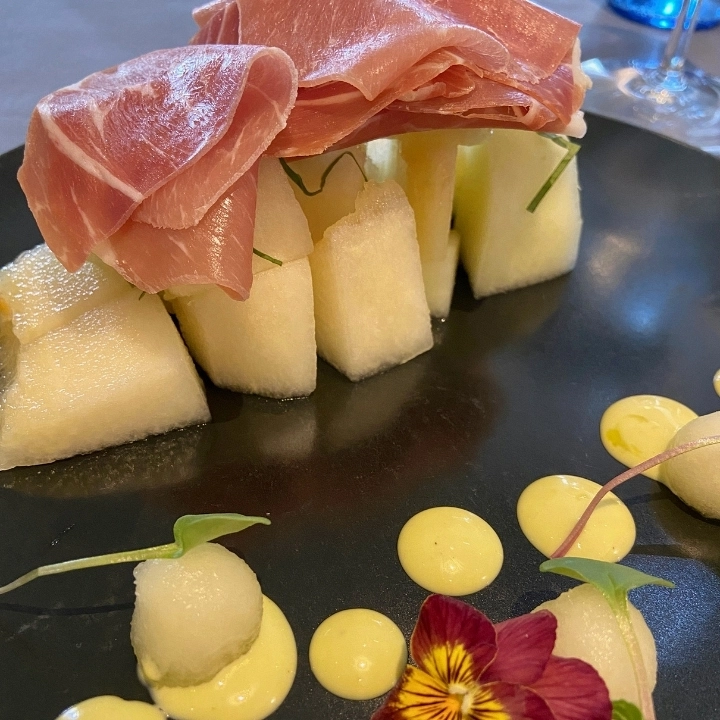 Presentación jamón con melón: exhuberante con flores y puntos de salsas
